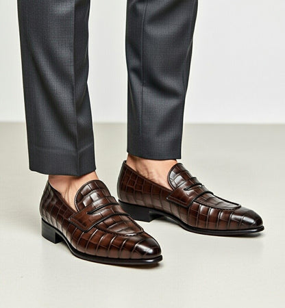 Brown dress shoes worn with dark gray pants on a light background