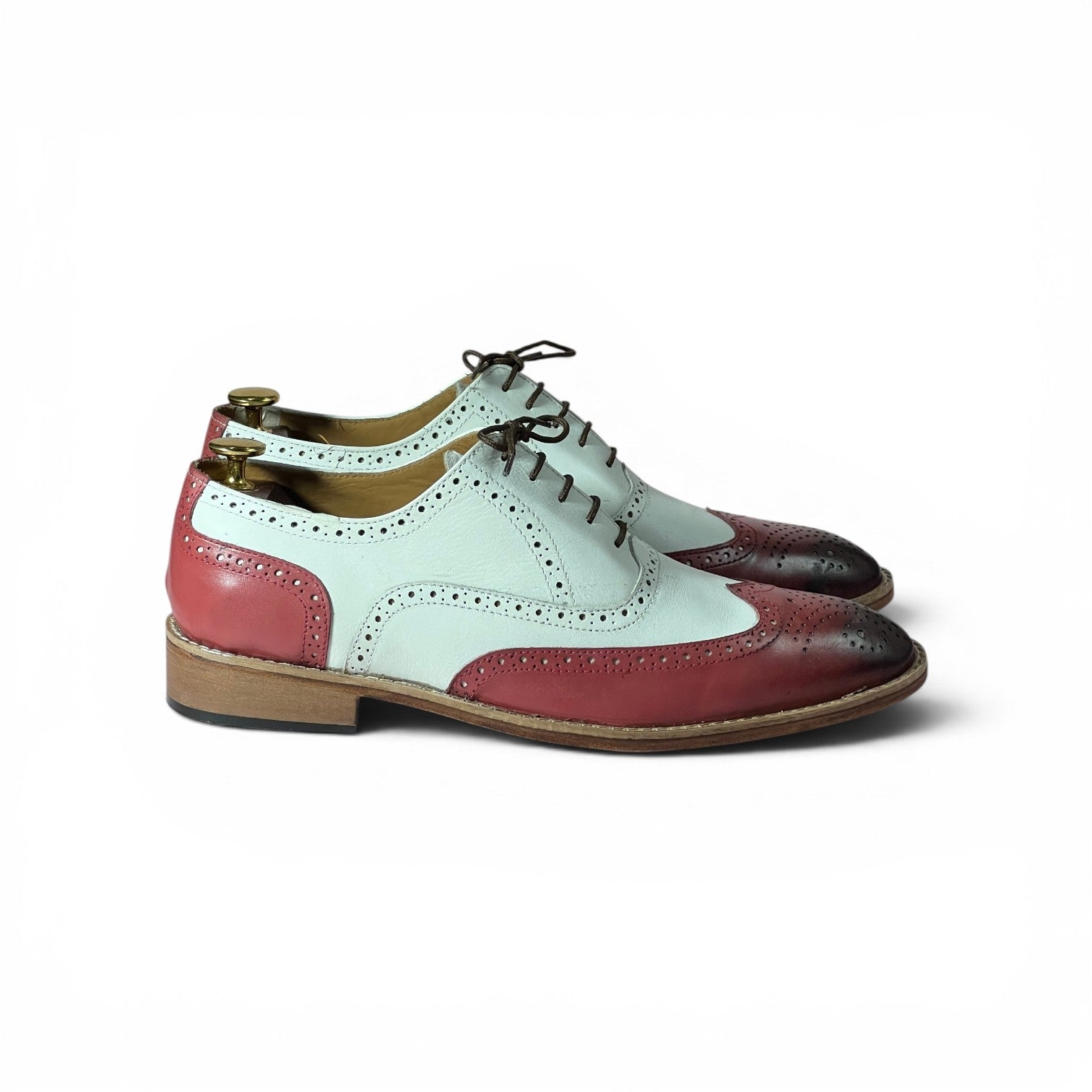 A pair of men's wingtip oxford shoes in a three-color leather pattern of pale mint green, dusty rose red, and dark brown, shown from a side profile on a white background.