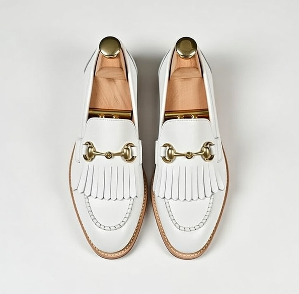 White loafers with gold accents on a light gray background