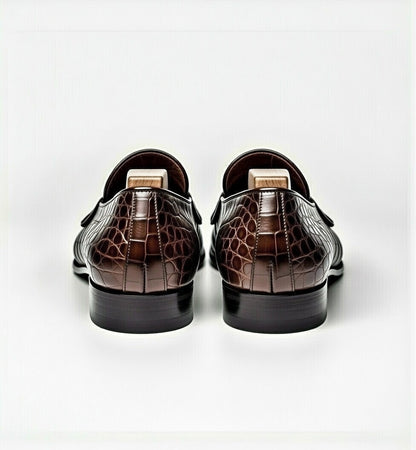 Pair of brown crocodile-patterned loafers on a white background