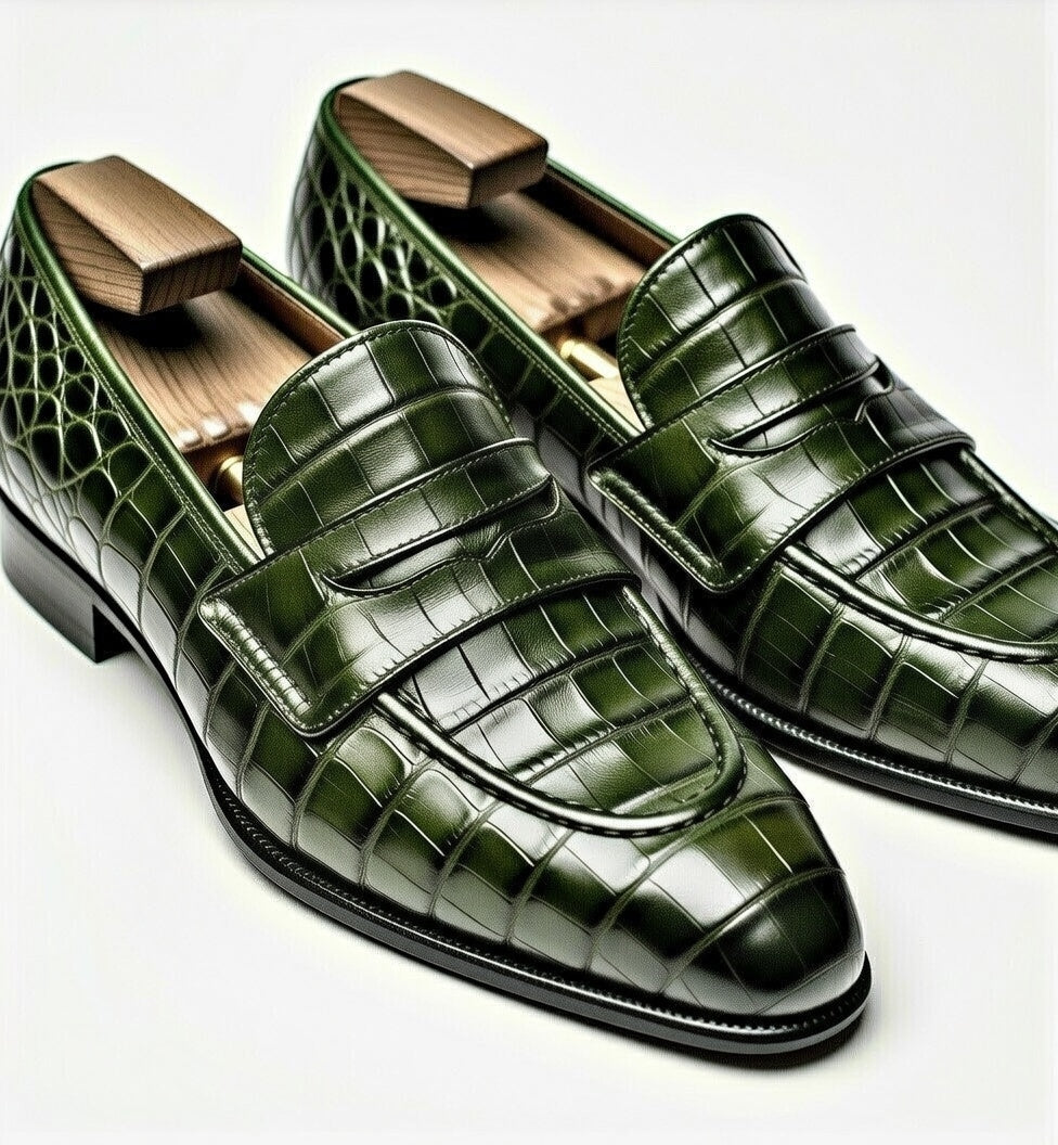 Green crocodile-patterned loafers on a white background