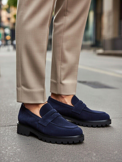 Navy loafers worn with beige pants on a city street.