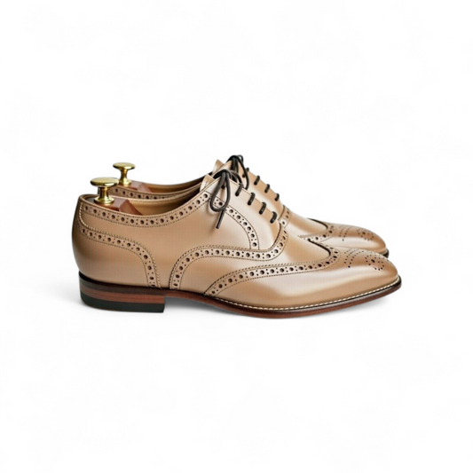 Pair of beige dress shoes with a white background