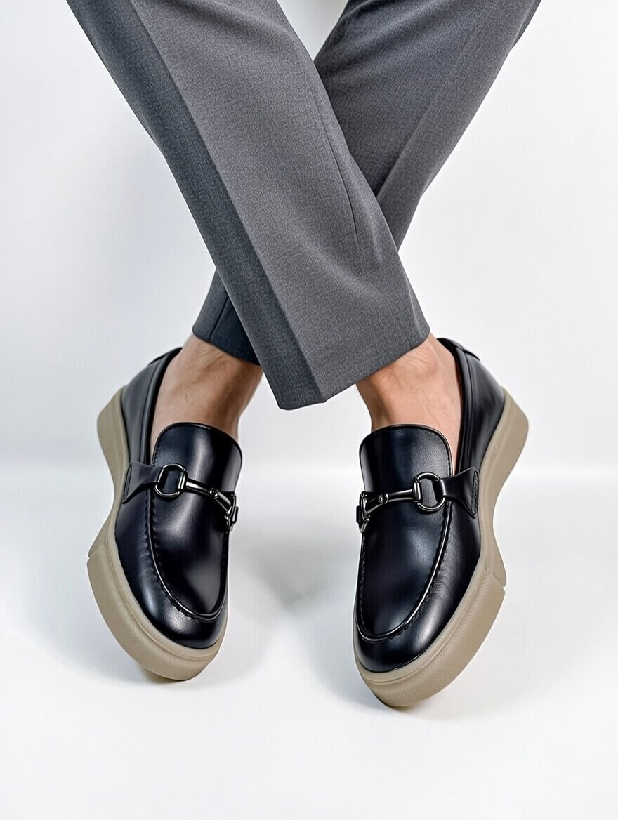 Black loafers worn with gray pants on a light gray background