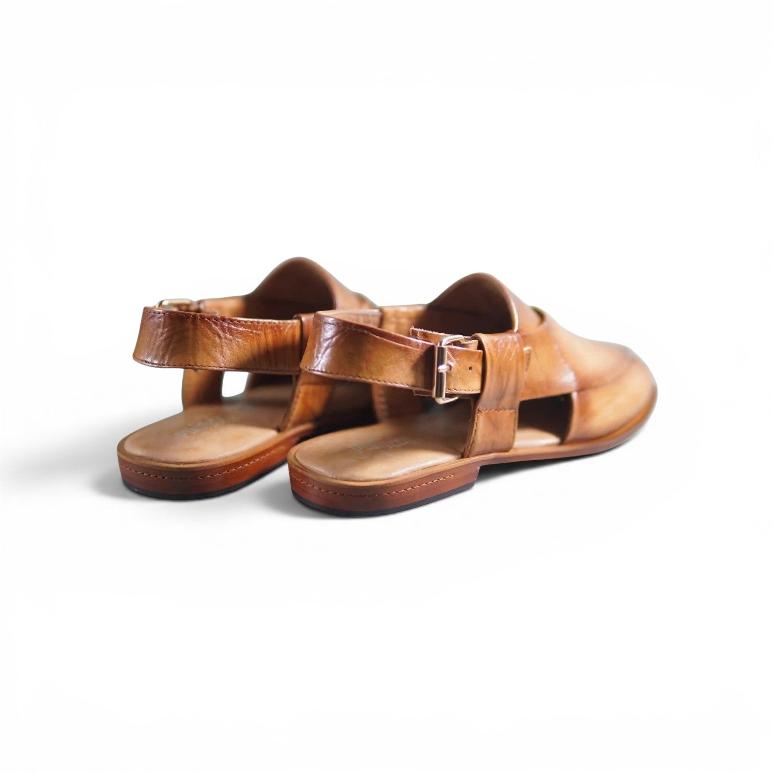 A pair of brown leather slide sandals with open toes and adjustable ankle straps with silver buckles, shown on a white background.