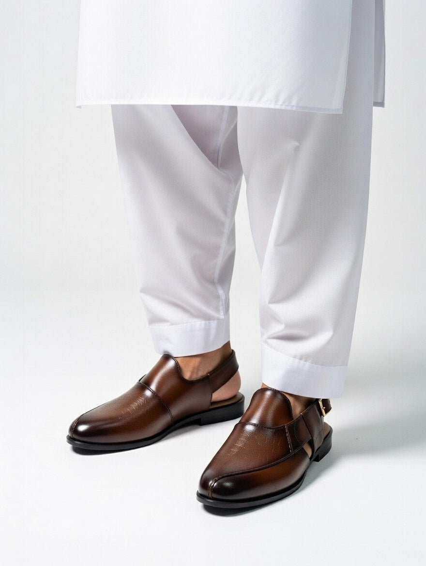 Brown dress shoes worn with white pants on a light gray background
