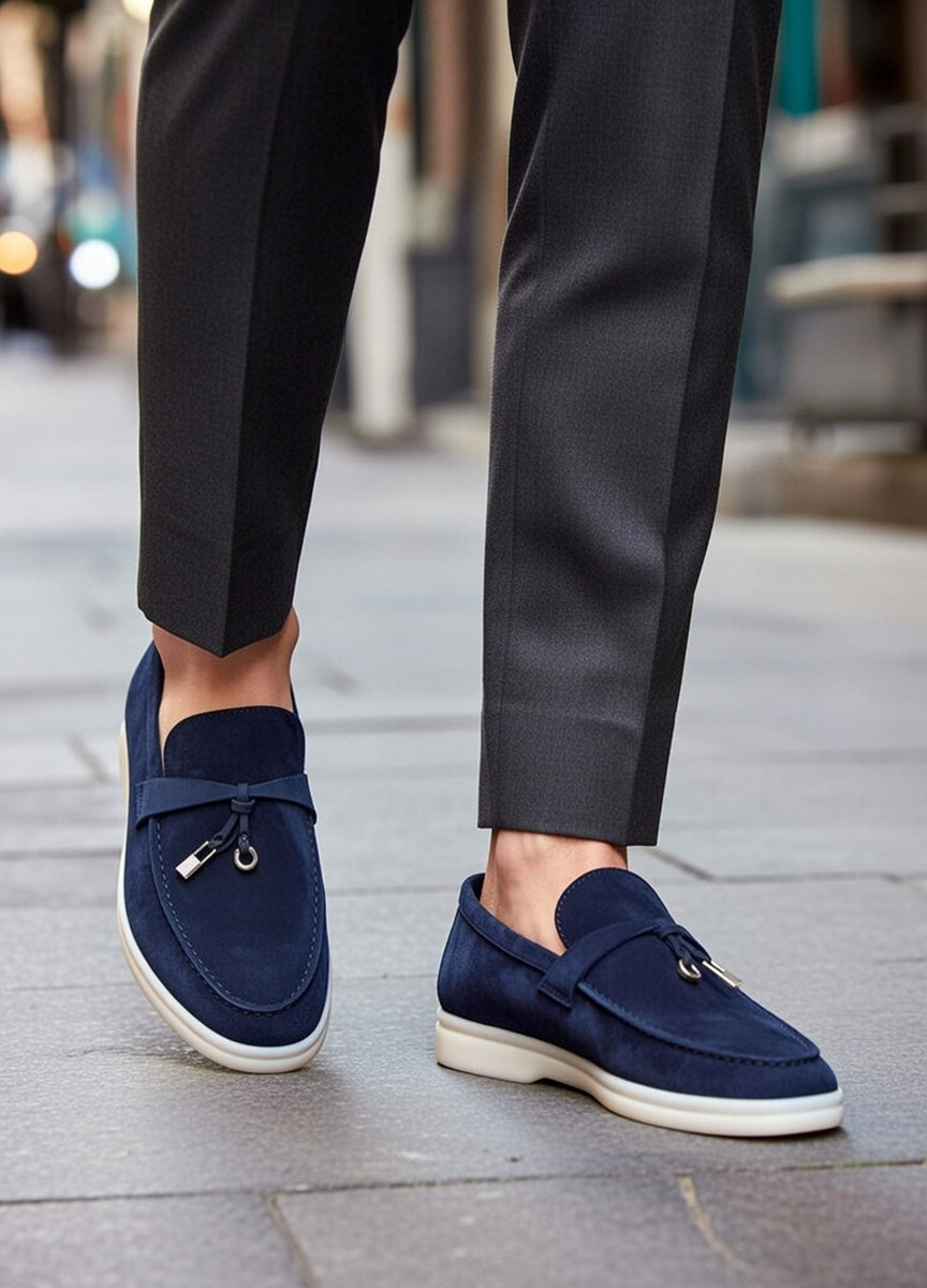 Navy loafers worn with black pants on a city street.