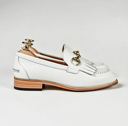White loafer shoe with gold accents on a light gray background