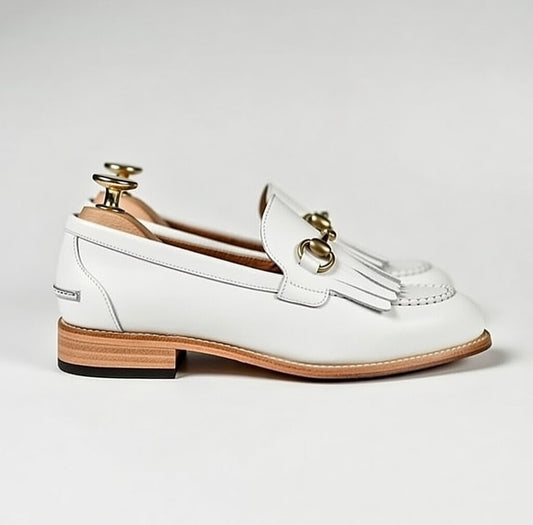 White loafer shoe with gold accents on a light gray background