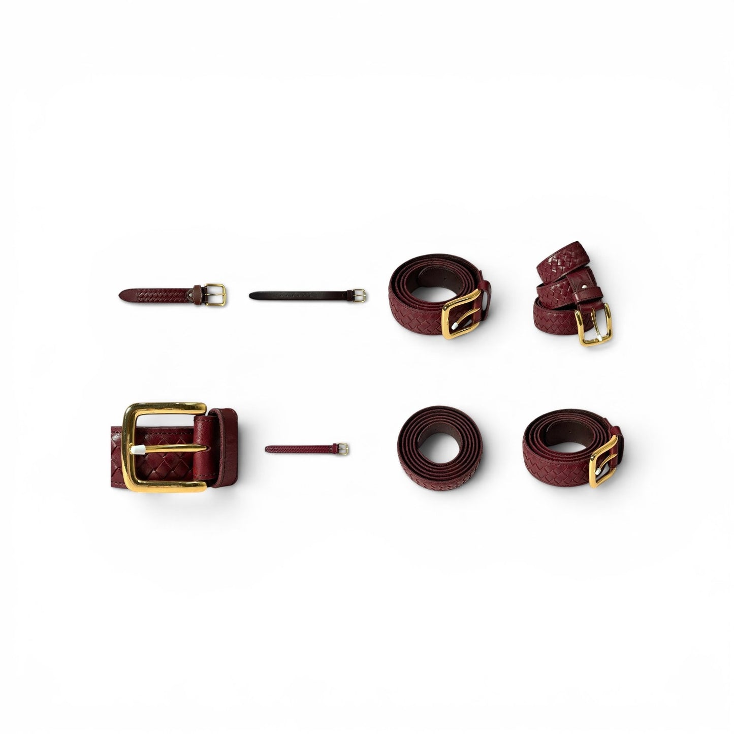 A set of burgundy leather belts with gold-tone hardware, including two flat belts, one rolled belt, one adjustable strap with a large buckle, and two small leather ties, arranged on a plain white background.