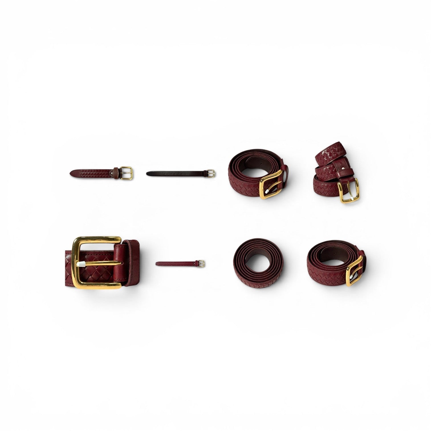 A set of burgundy leather belts with gold-tone hardware, including two flat belts, one rolled belt, one adjustable strap with a large buckle, and two small leather ties, arranged on a plain white background.