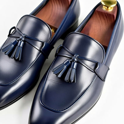 Pair of navy blue loafers with tassels on a white background