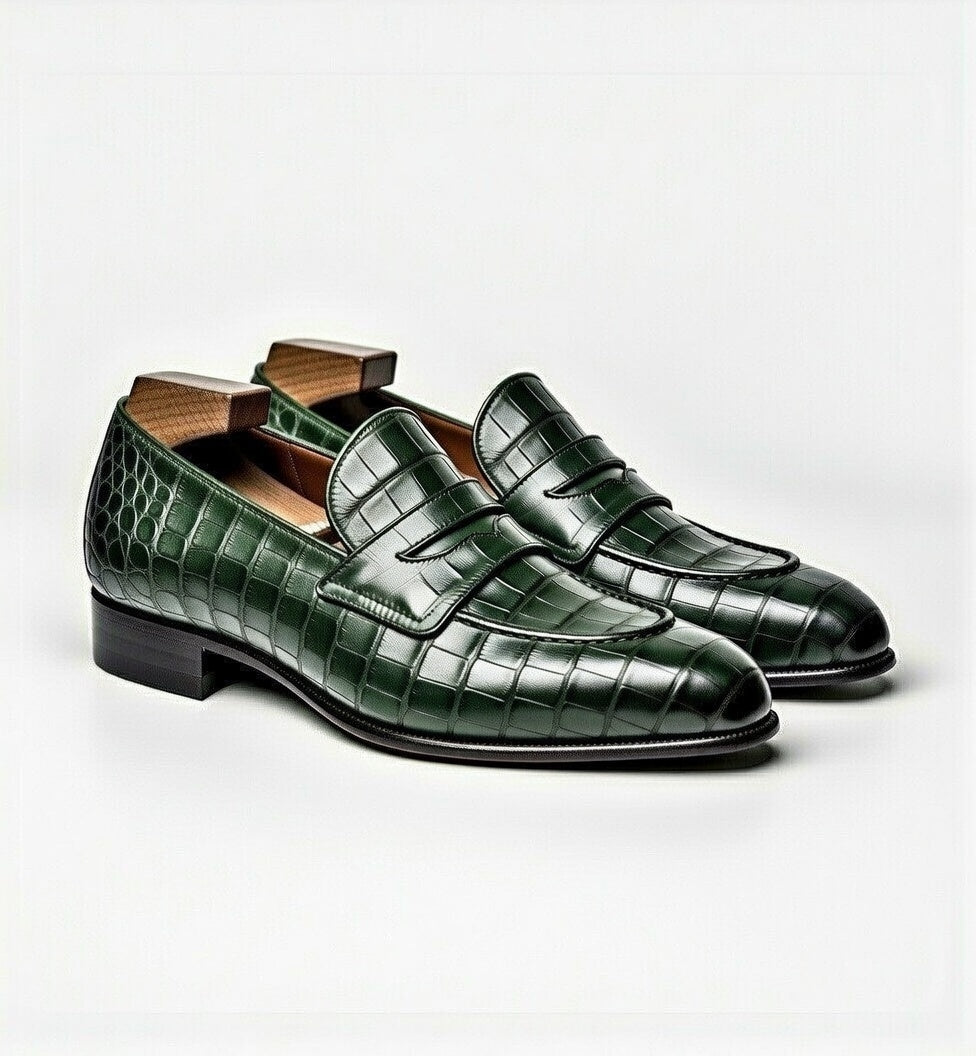 Green crocodile-patterned loafers on a white background