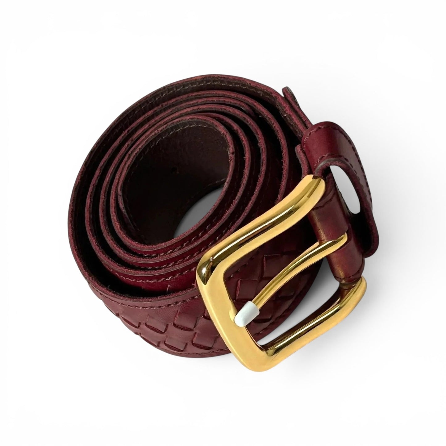 A dark burgundy woven leather belt with a polished gold buckle, coiled on a clean white background.