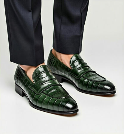 Green crocodile-patterned loafers worn with black pants on a light gray background