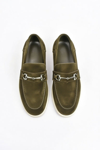 Pair of green loafers with metallic buckles on a white background