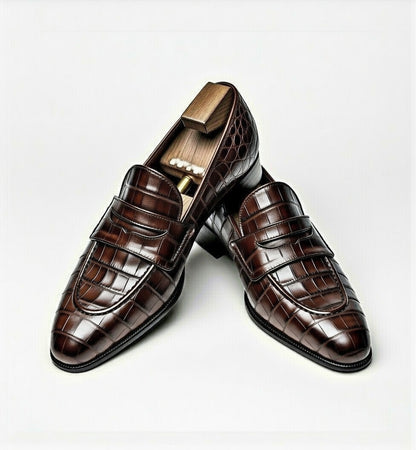 Brown crocodile-patterned loafers on a white background