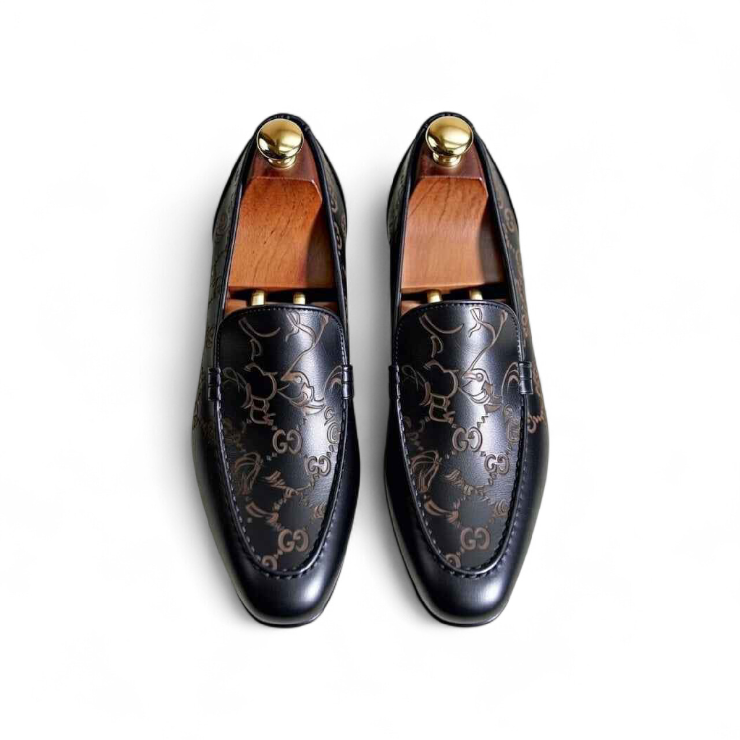 Pair of black loafers with gold accents on a white background