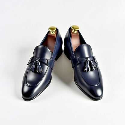 Pair of navy loafers with tassels on a light gray background