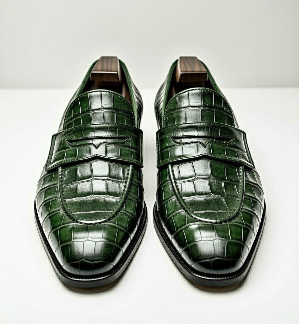 Pair of green crocodile-patterned loafers on a white background