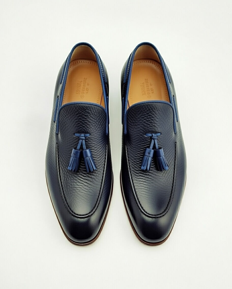 Pair of navy blue loafers with tassels on a white background