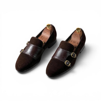 A pair of dark brown double strap loafers with suede and leather panels, gold-tone buckle details, and gold shoe tree inserts, shown on a clean white background.