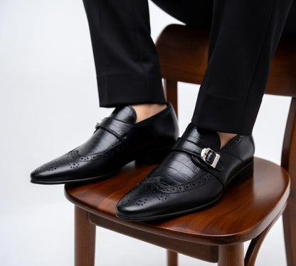 Black leather dress shoes with a silver buckle on a wooden chair.