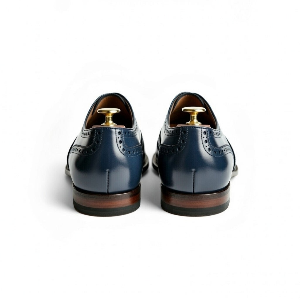 Pair of blue dress shoes with brown soles on a white background
