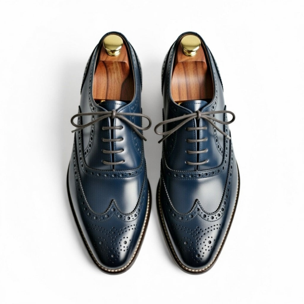 Pair of blue dress shoes with gold buttons on a white background