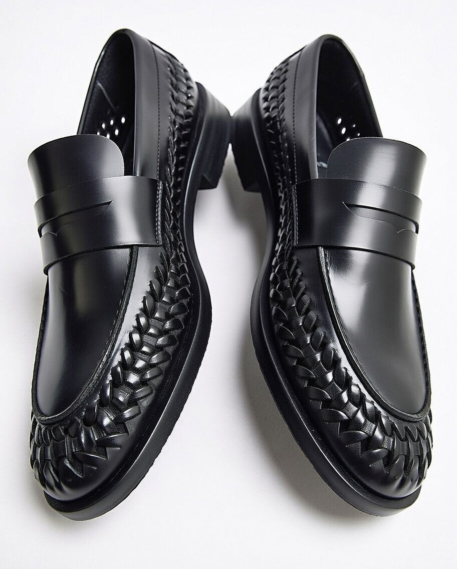 Black leather loafers with woven detailing on a white background