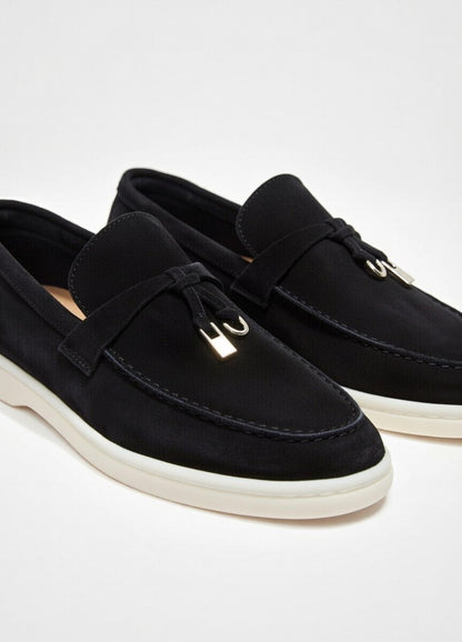 Black loafers with white soles on a light gray background
