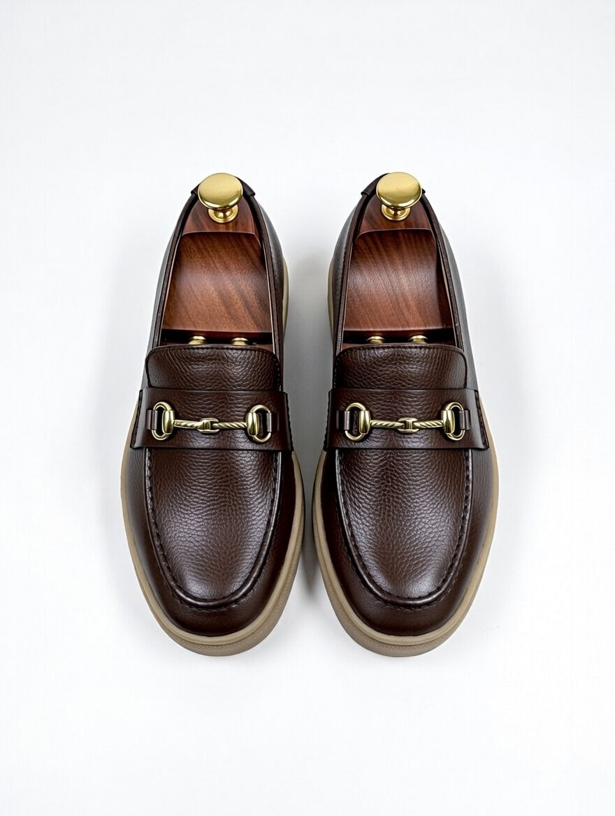 Pair of brown leather loafers with gold accents on a white background
