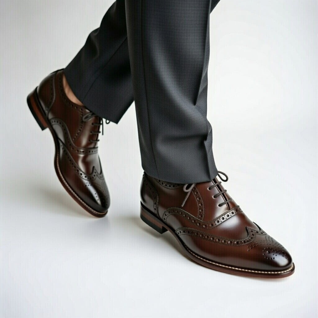 Brown dress shoes worn with dark gray pants on a light background
