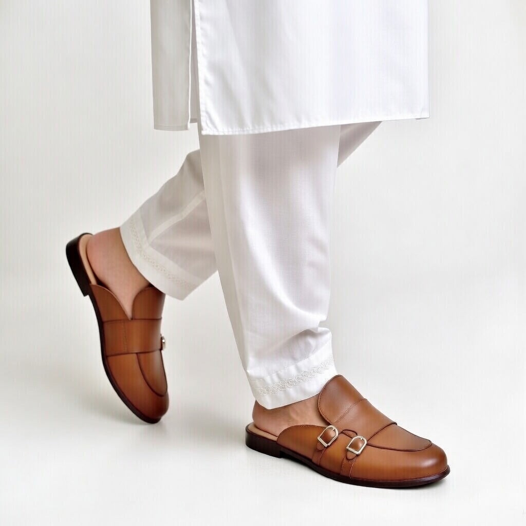 Brown loafers worn with white pants on a light background