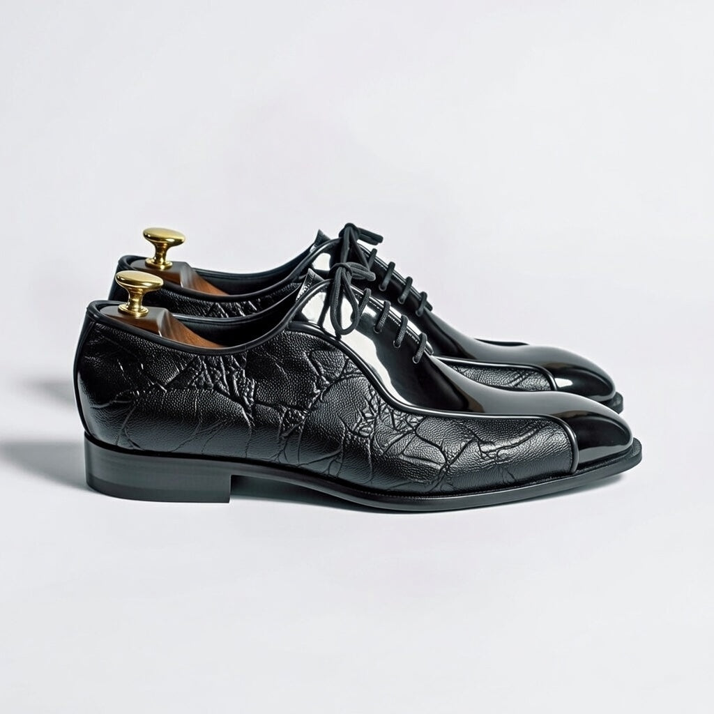 Black leather shoes with unique toe design on a light gray background