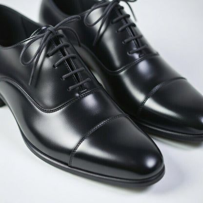 Pair of black dress shoes on a light gray background