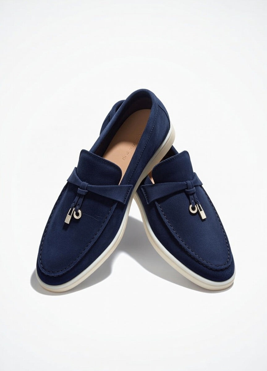 Pair of navy blue loafers with white soles on a light gray background