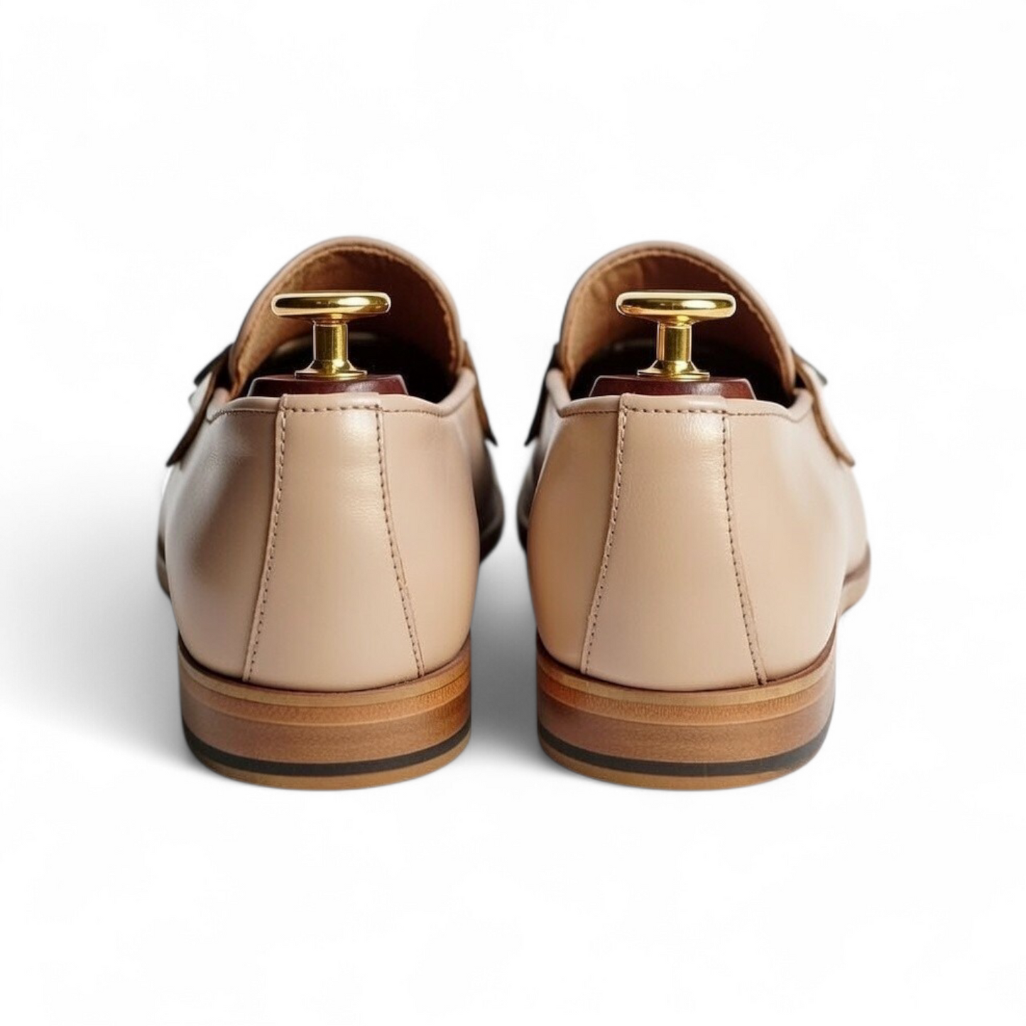 Pair of beige loafers with gold tacks on a white background