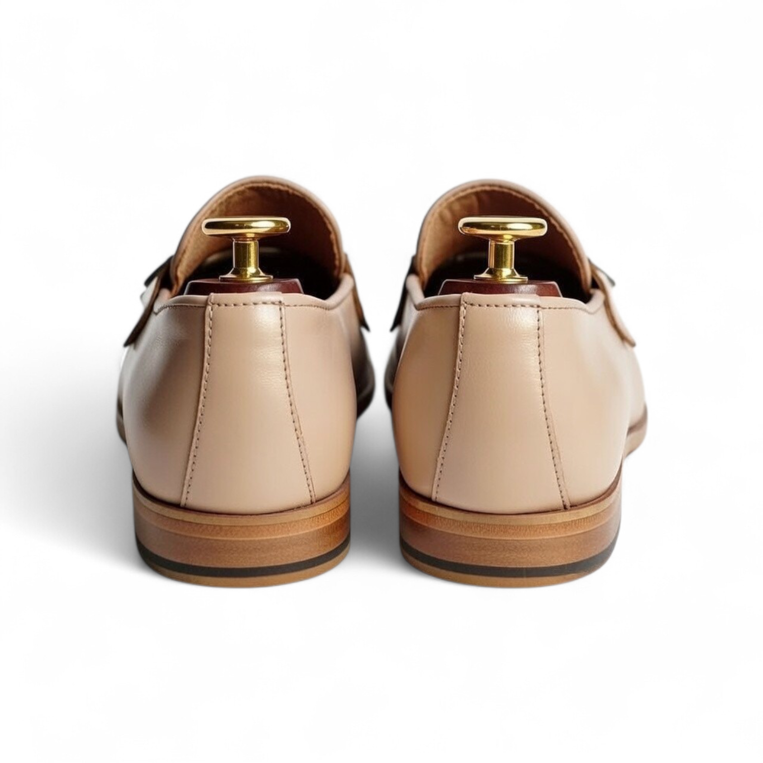 Pair of beige loafers with gold tacks on a white background
