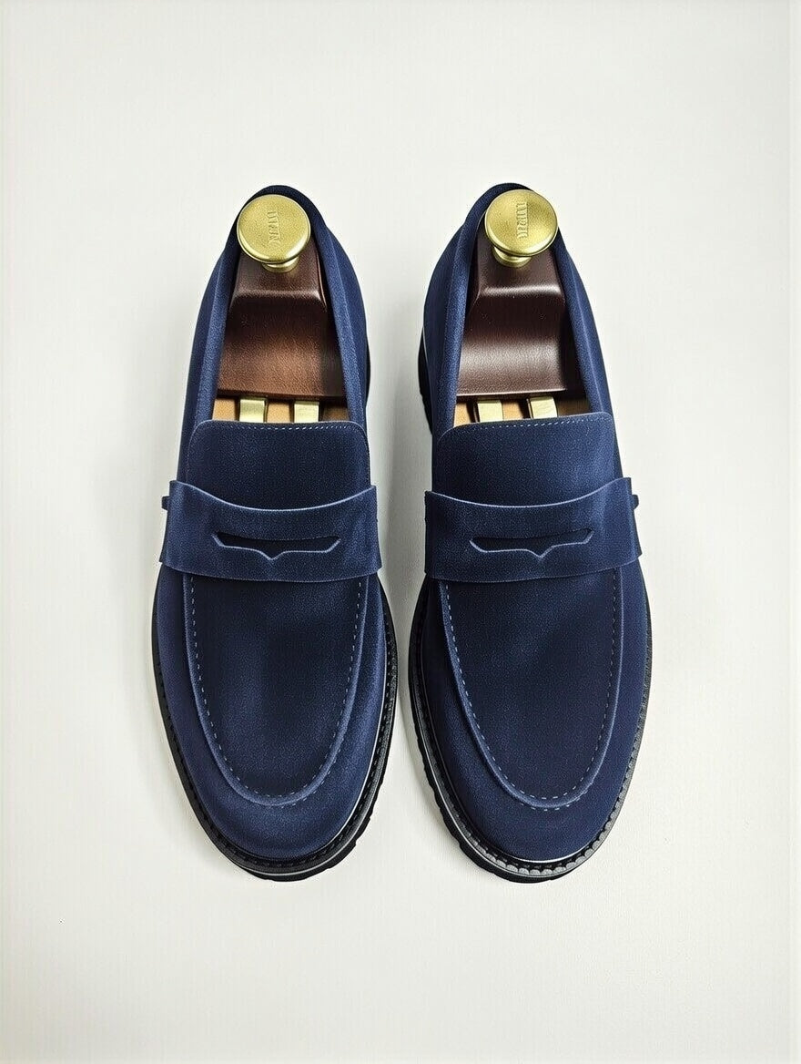 Pair of blue loafers with gold accents on a light gray background