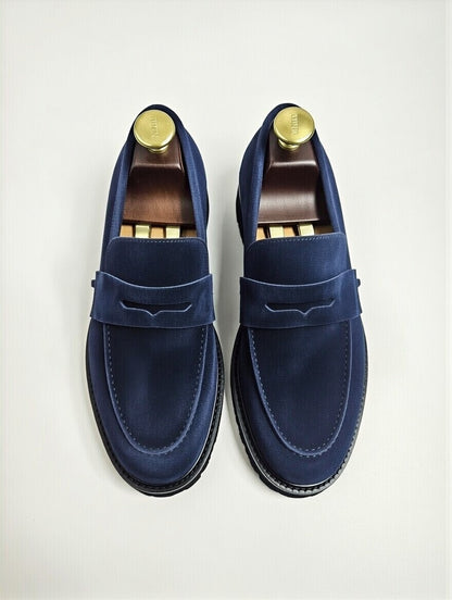 Pair of blue loafers with gold accents on a light gray background