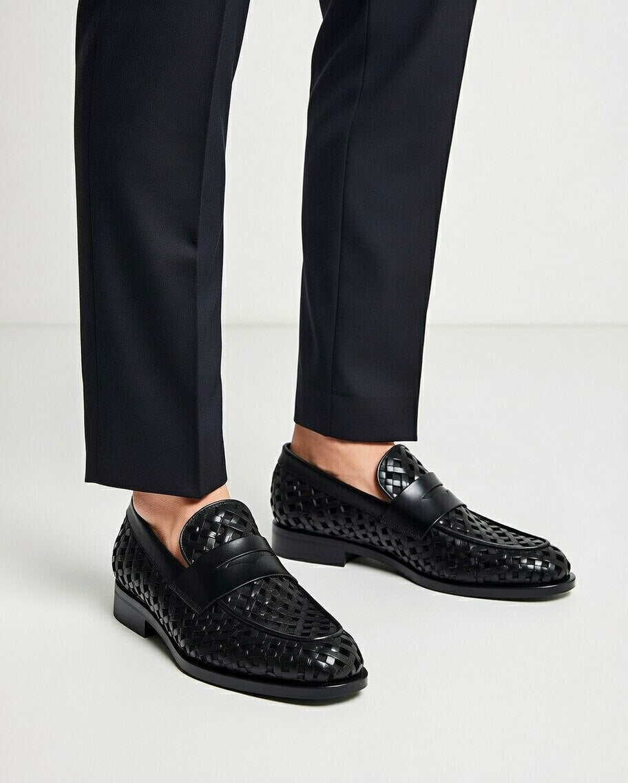 Black loafers worn with black pants on a light background