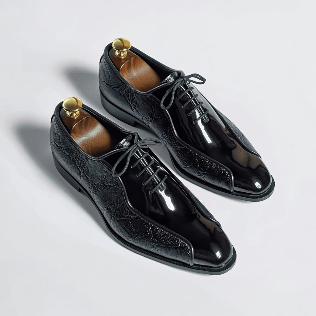 Pair of black dress shoes with brown soles on a light gray background