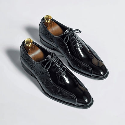 Pair of black dress shoes with brown soles on a light gray background