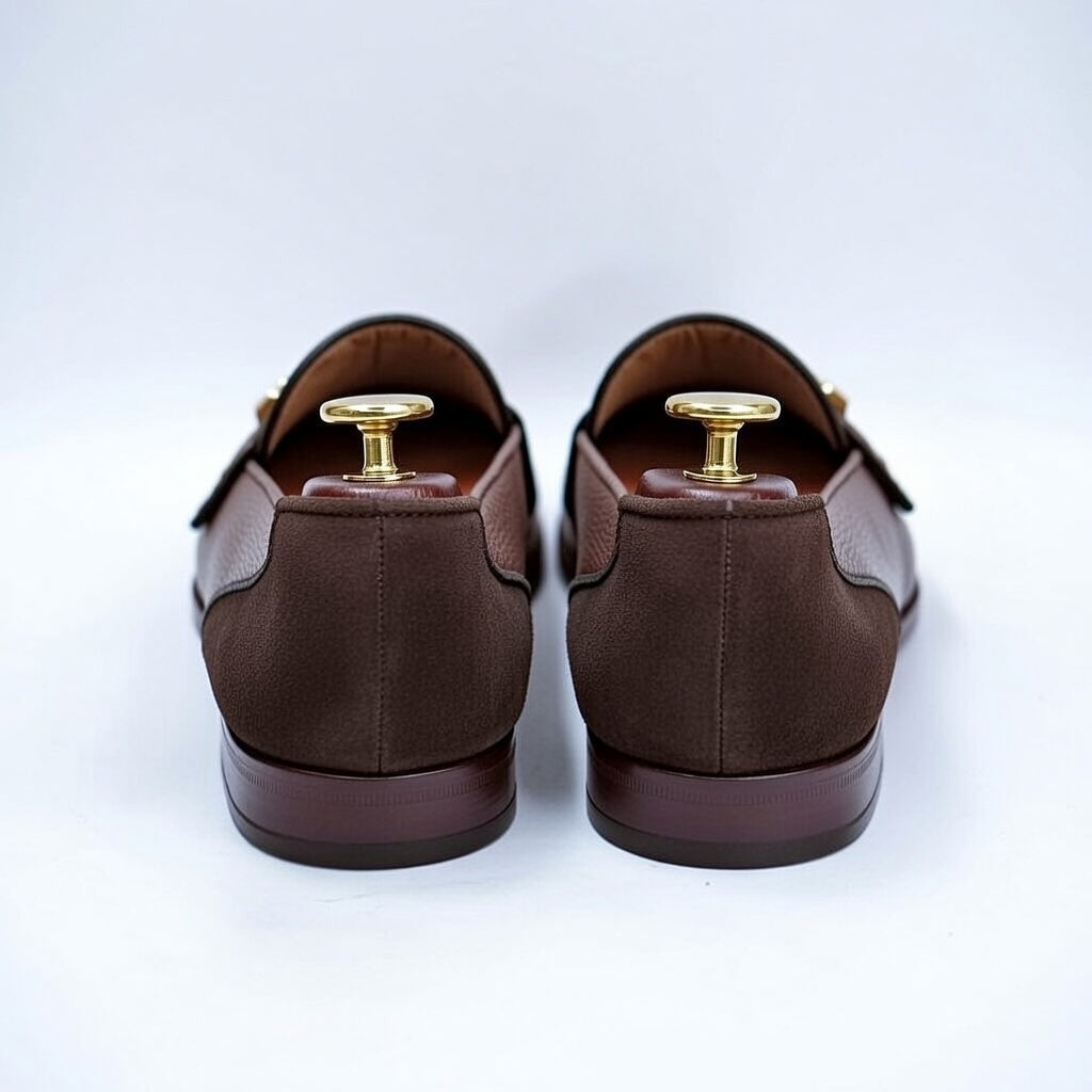 Pair of brown loafers with gold accents on a white background