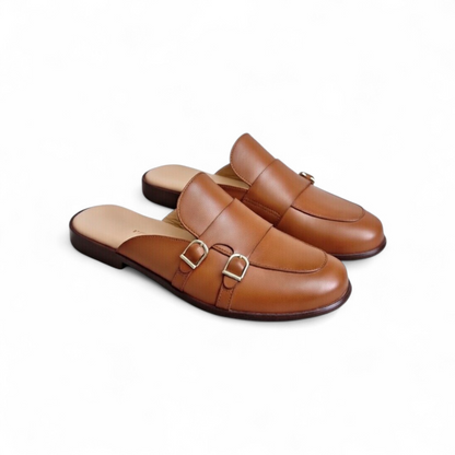 Pair of brown leather mules with buckles on a white background