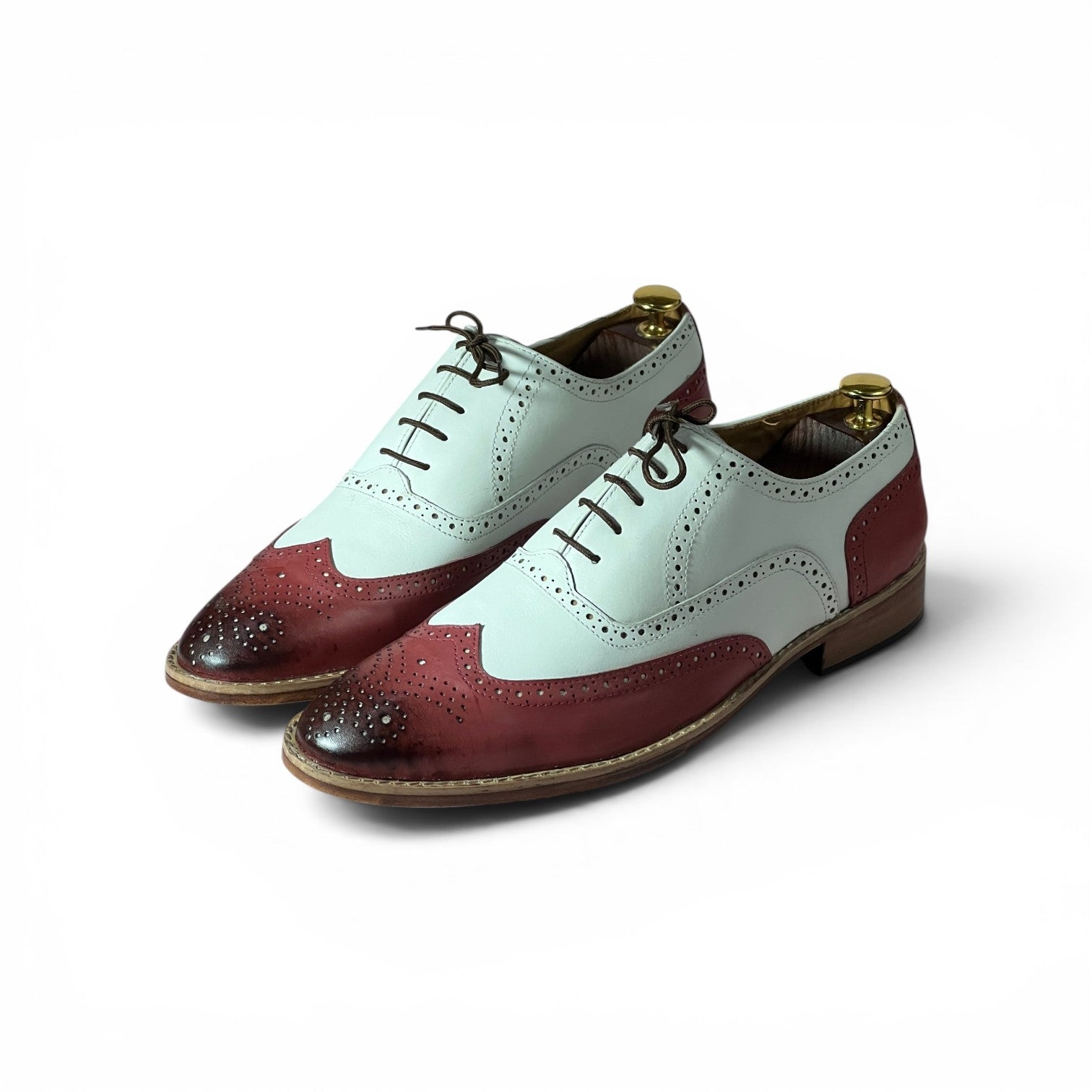 A pair of men's wingtip oxford shoes with a color-blocked design featuring a pale mint green upper and a deep burgundy toe cap, finished with dark brown laces and a brown sole, shown on a white background.