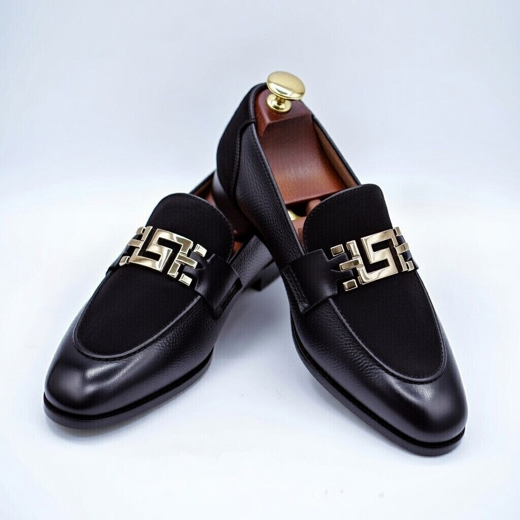 Black loafers with gold decorative bands on a light gray background