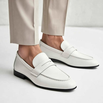 White loafers worn with beige pants on a light gray background