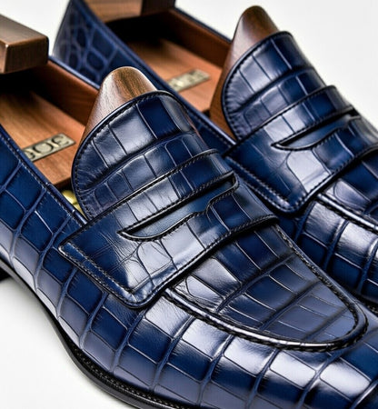 Blue crocodile-patterned loafers with wooden soles in a wooden shoe box.